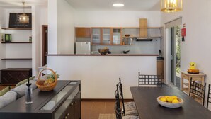 Een moderne keuken met houten kastjes, een eethoek met tafel en stoelen, en uitzicht op de omgeving.