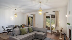 Een woonkamer met een hoekbank, een eettafel met stoelen, een televisie en een open haard.