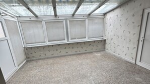 Een kamer met een schuine plafond, dakramen, een behang met patroon, een betegelde vloer en een deur met een 'HELLO' mat.