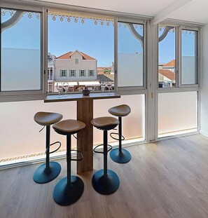 Ein Zimmer mit großem Fenster, einem Holztisch und vier Barhocker.