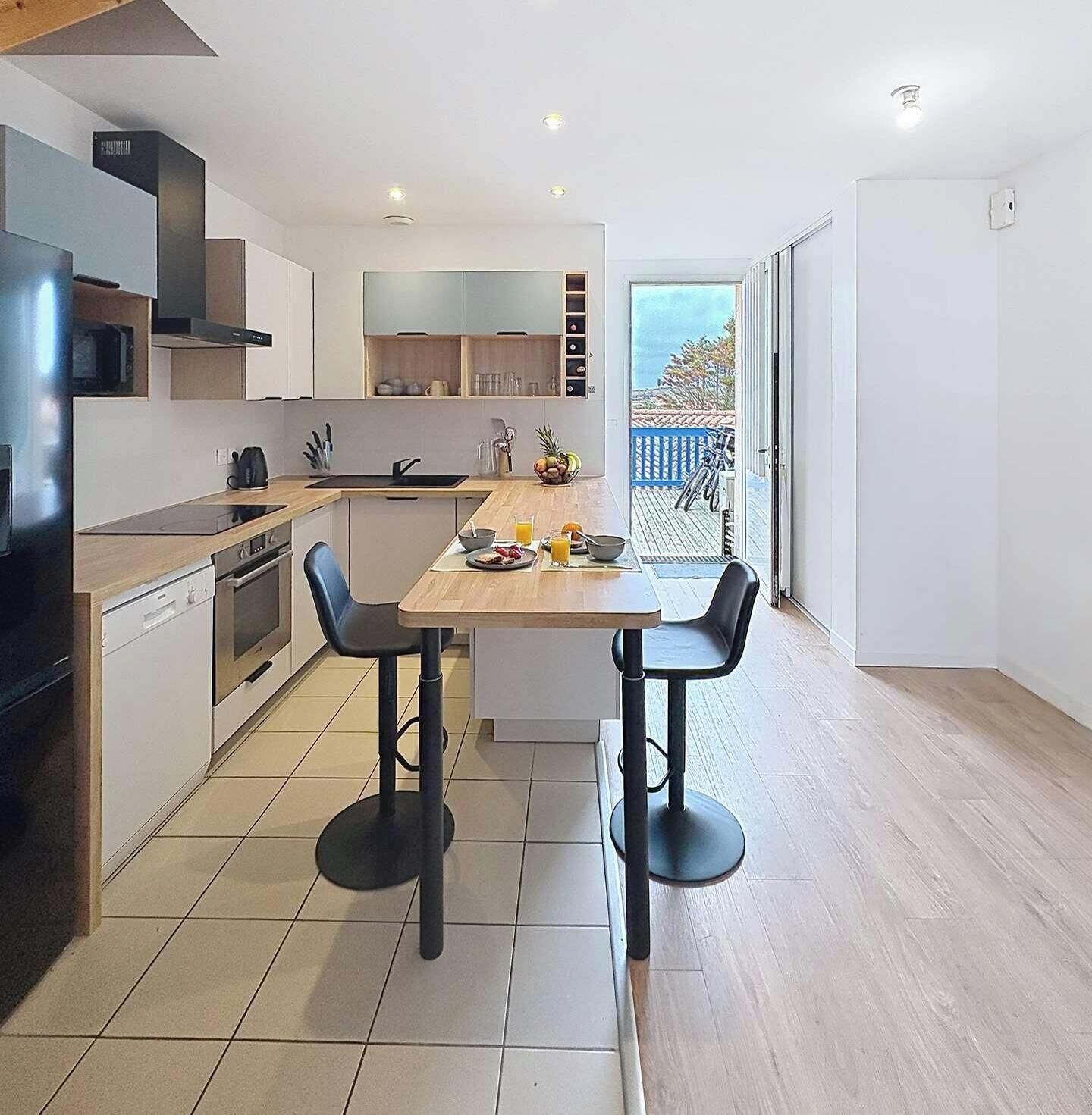 A modern kitchen with a dining area, a dishwasher, and a view of the outdoors.