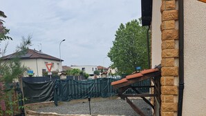 A patio area with a stone wall, a wooden deck, and a covered seating area.