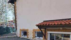 A building with a stone foundation, a tiled roof, and a large sliding glass door.