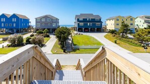 A residential area with a wooden deck, a clear sky, and houses with a uniform architectural style. - Sunny Hideaway | Oceanside | Walk to Beach | Deck (Emerald Isle)