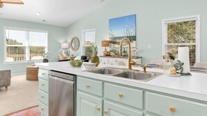 A kitchen with a large island, double sinks, and a ceiling fan. - Sunny Hideaway | Oceanside | Walk to Beach | Deck (Emerald Isle)