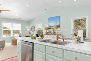 A kitchen with a large island, double sinks, and a ceiling fan. - Sunny Hideaway | Oceanside | Walk to Beach | Deck (Emerald Isle)