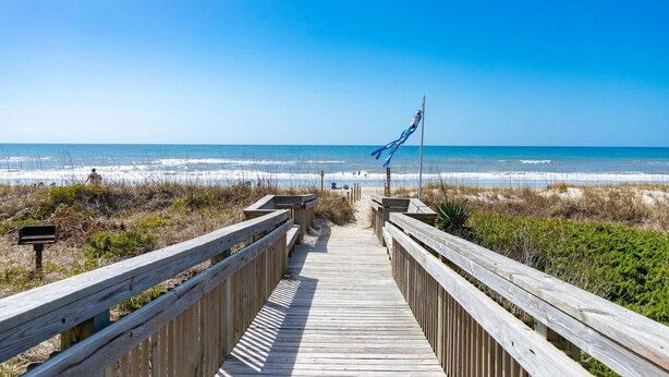 A wooden boardwalk leading to a beach with a clear view of the ocean. - Sunny Hideaway | Oceanside | Walk to Beach | Deck (Emerald Isle)