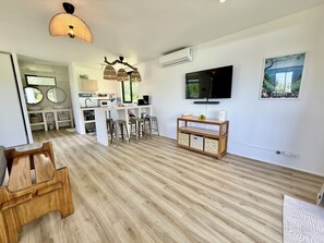 Eine moderne Küche mit einer zentralen Kochinsel, Barhocker, einem Fernseher und einer Wand-Klimaanlage.