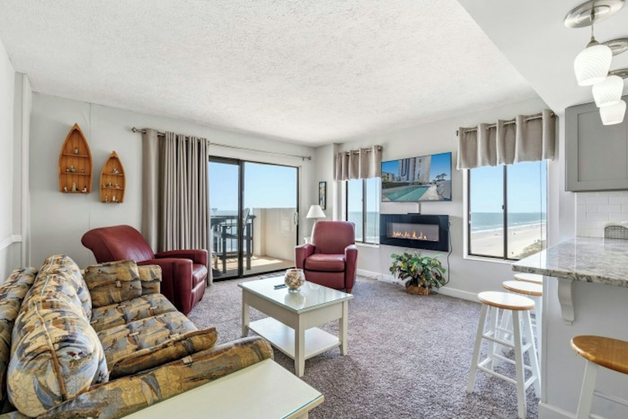 Un salon comprenant un canapé, des fauteuils, une table basse, une cheminée et une vue sur la plage.