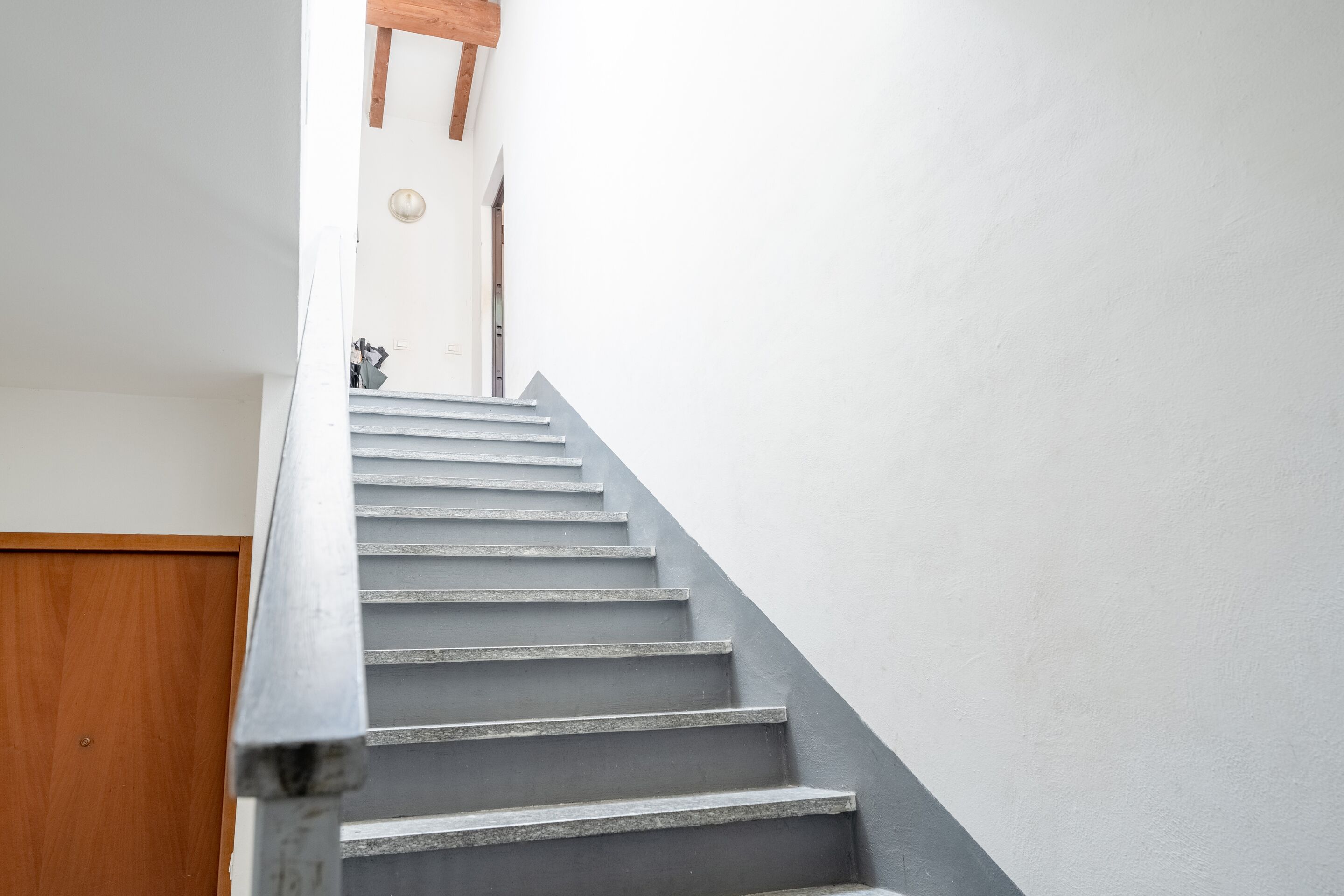 Eine Treppe mit einer Holztür unten und einer weißen Wand darüber.