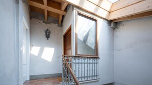 Un escalier avec une rampe en bois, une fenêtre avec un cadre en bois et un luminaire fixé au mur.