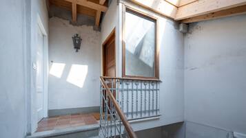 Una escalera con barandilla de madera, un ventanal con marco de madera y un aplique de pared.