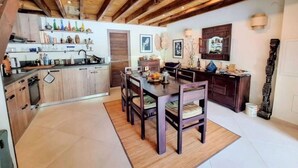 A spacious kitchen with wooden beams, a dining area with a table and chairs, and a decorative wall with framed artwork. - Coeur de Marina, Anse Marcel Beach within Walking Distance,  full AC (Anse Marcel)