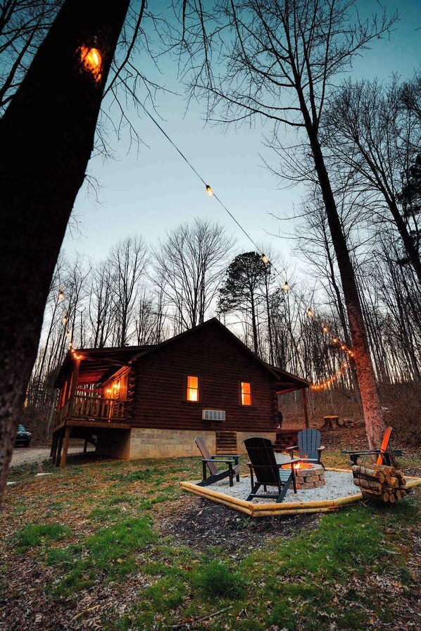 Un chalet rustique doté d’une terrasse, d’un foyer et de meubles pour se détendre à l’extérieur.