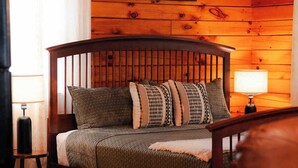 A cozy room with a wooden bed, a lamp, and a painting on the wall. - Secluded Cozy Log Cabin Villa (Creola)