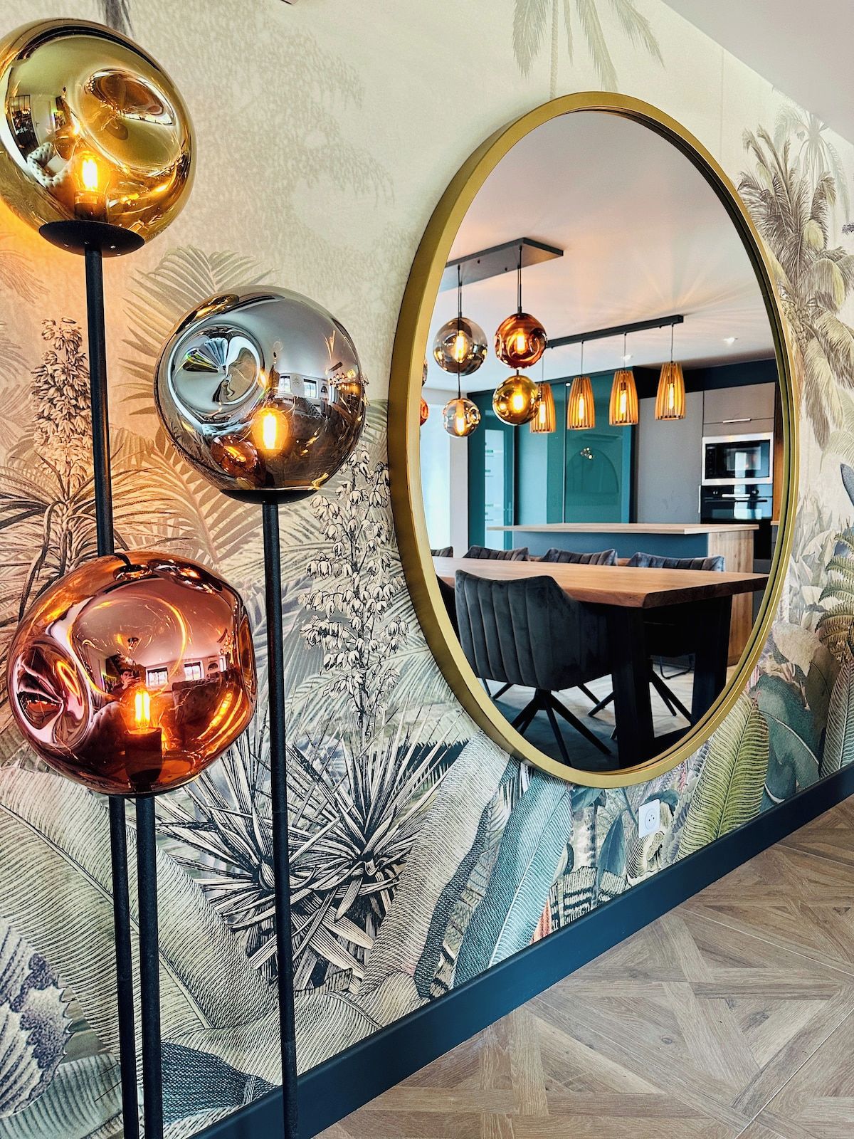 Un intérieur moderne comprenant un coin repas, une cuisine et un grand miroir qui agrandit visuellement l’espace.