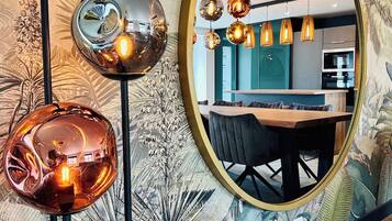 Un intérieur moderne comprenant un coin repas, une cuisine et un grand miroir qui agrandit visuellement l’espace.