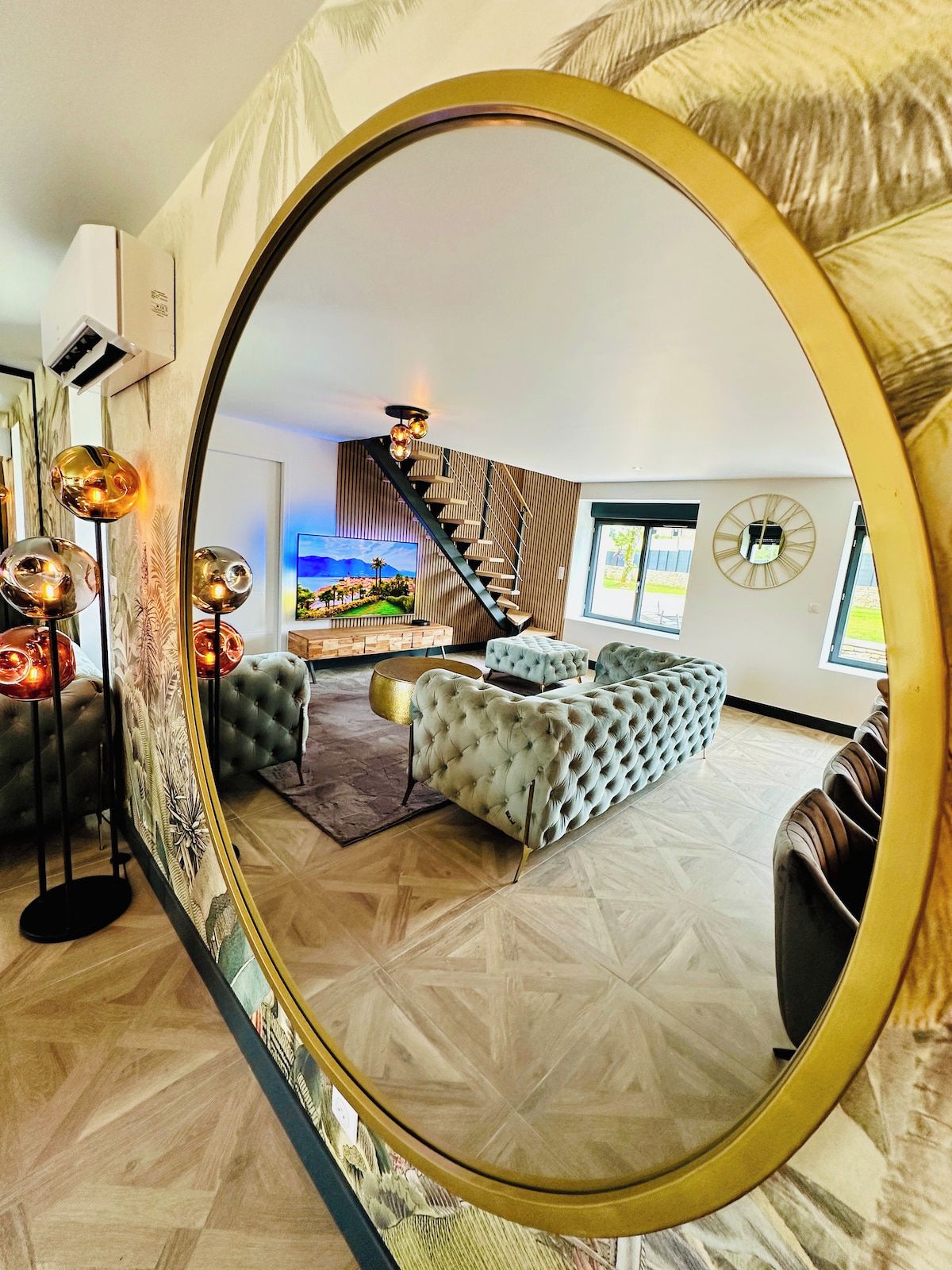Een moderne woonkamer met een grote spiegel, een trap en uitzicht op de omgeving.
