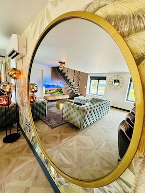 A modern living room with a large mirror, a staircase, and a view of the outdoors. - La Bastide du Causse - Domaine Gouloumès (Ginouillac)