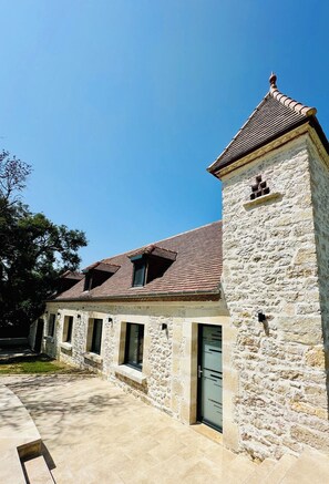 Ein Gebäude aus Stein mit einem Ziegeldach, einer Tür und Fenstern.