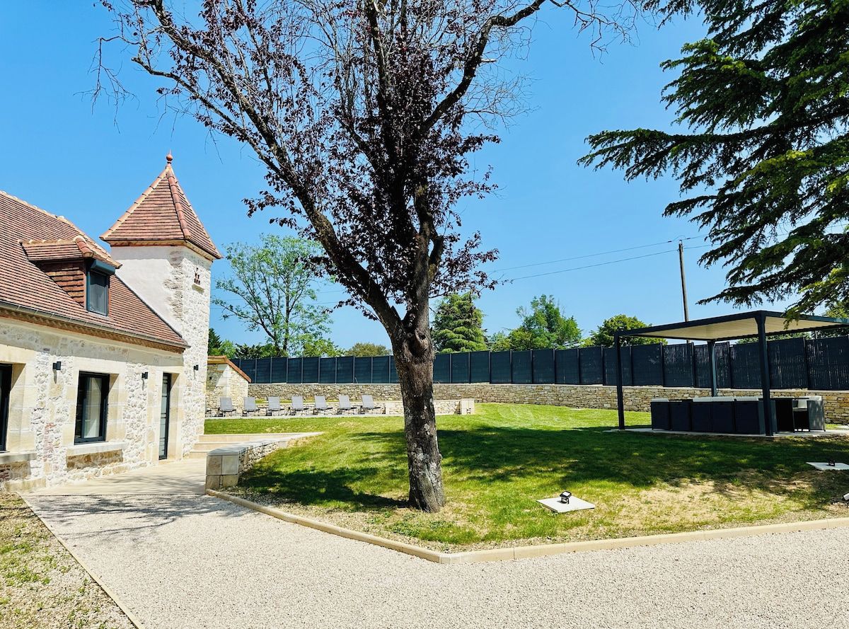 Ein Gebäude mit einer Stein-Fassade, einem Ziegeldach und einem Baum im Vordergrund.