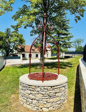 Una estructura circular de piedra con una escalera en espiral de metal, rodeada de césped y árboles.