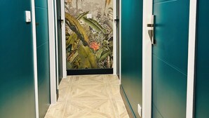 A hallway with teal walls, a tiled floor, and a mural of tropical foliage. - La Bastide du Causse - Domaine Gouloumès (Ginouillac)
