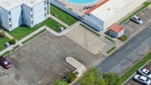 Eine Übersichtsansicht eines Grundstücks mit Schwimmbad, einem Gebäude mit rotem Dach und einem Parkplatz.