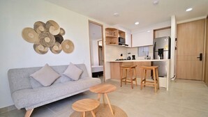 Een moderne woonkamer met een bank, twee kleine houten tafels en een geweven vloerkleed.