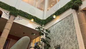 Een meerlaags atrium met dakraam, houten balken en een centrale kolom met een plant.