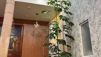 Un comedor con techo alto, una planta grande y un cuadro en la pared.