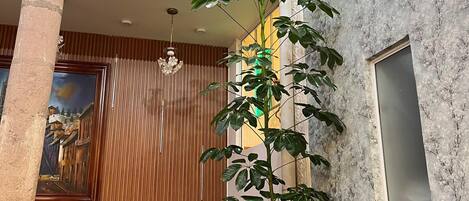 Un comedor con techo alto, una planta grande y un cuadro en la pared.