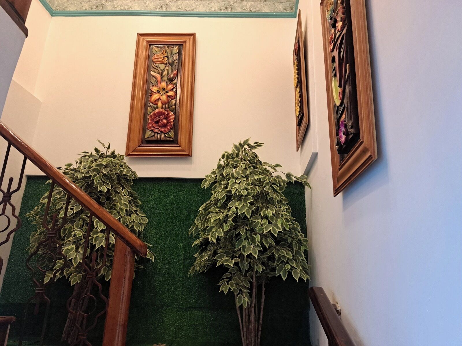 Eine Treppe mit grüner Wand, Holzgeländer und zwei Blumentöpfen.
