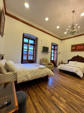 A hotel room with two beds, a TV, a chandelier, and wooden flooring. - Rossa Mia Hotel Boutique (Quito)