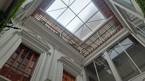Een gebouw met een dakraam, houten deuren en witte zuilen.