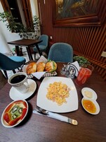 Et spisebord med morgenmadsprodukter, herunder croissanter, røræg og frugt.