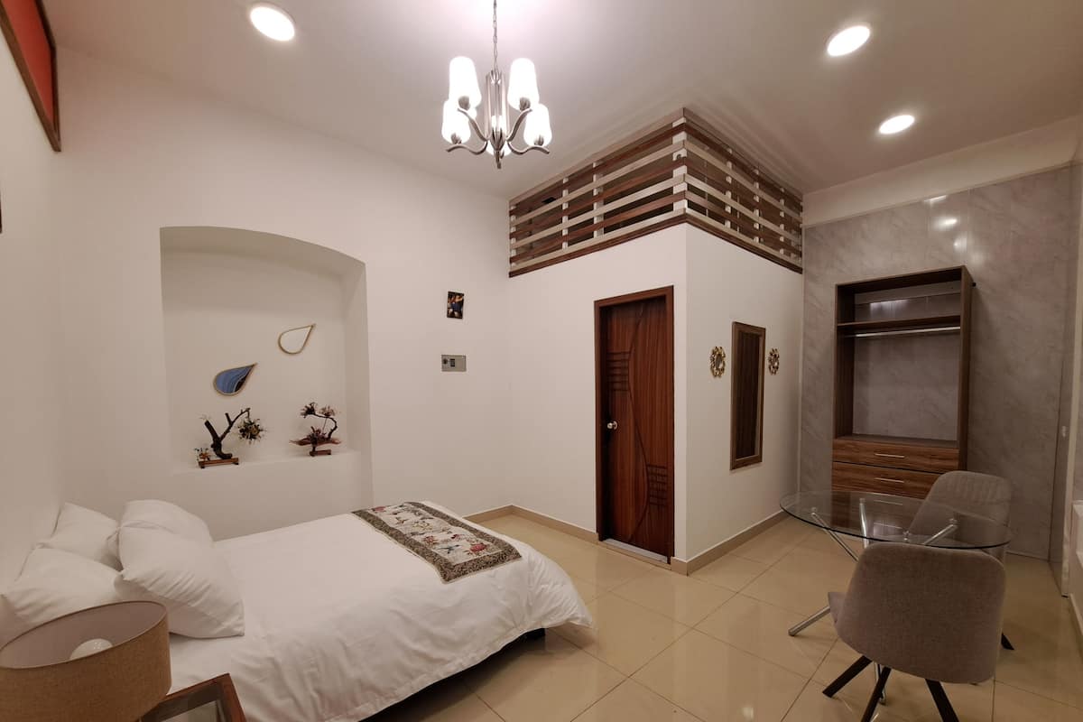 Un dormitorio con cama, una silla, armario y candelabro.