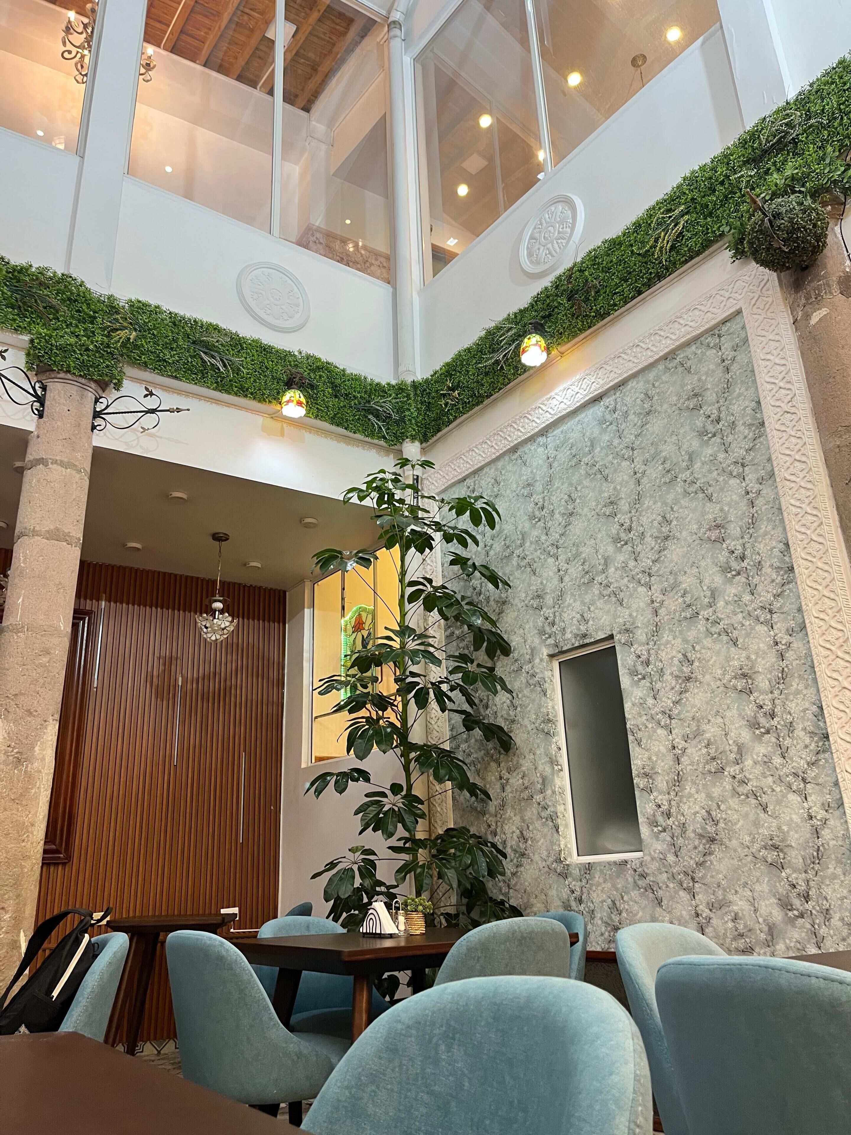 Un comedor con techo alto, una planta grande y una pared de mármol.
