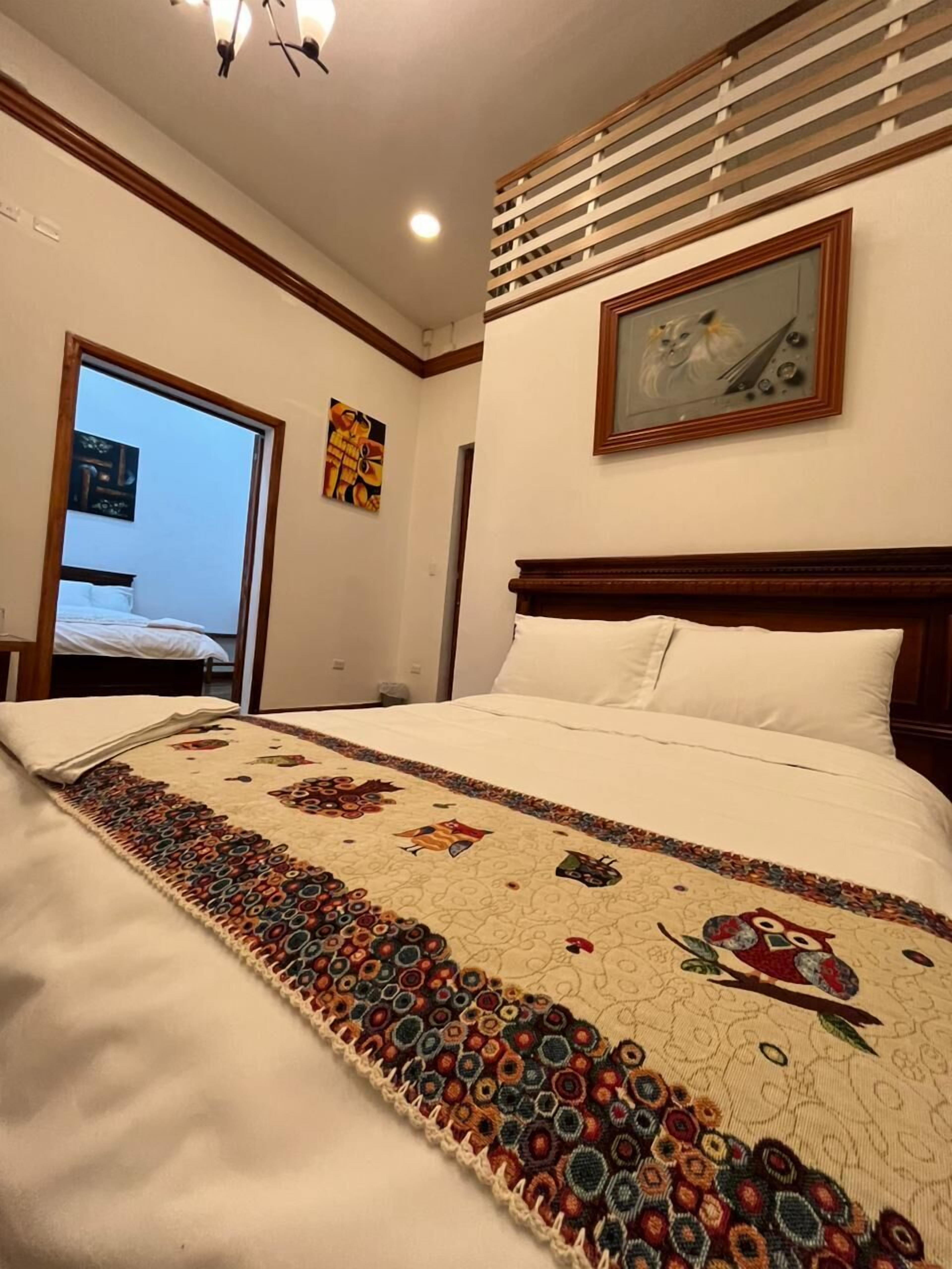 A hotel room with a bed, a painting, and a window with blinds.