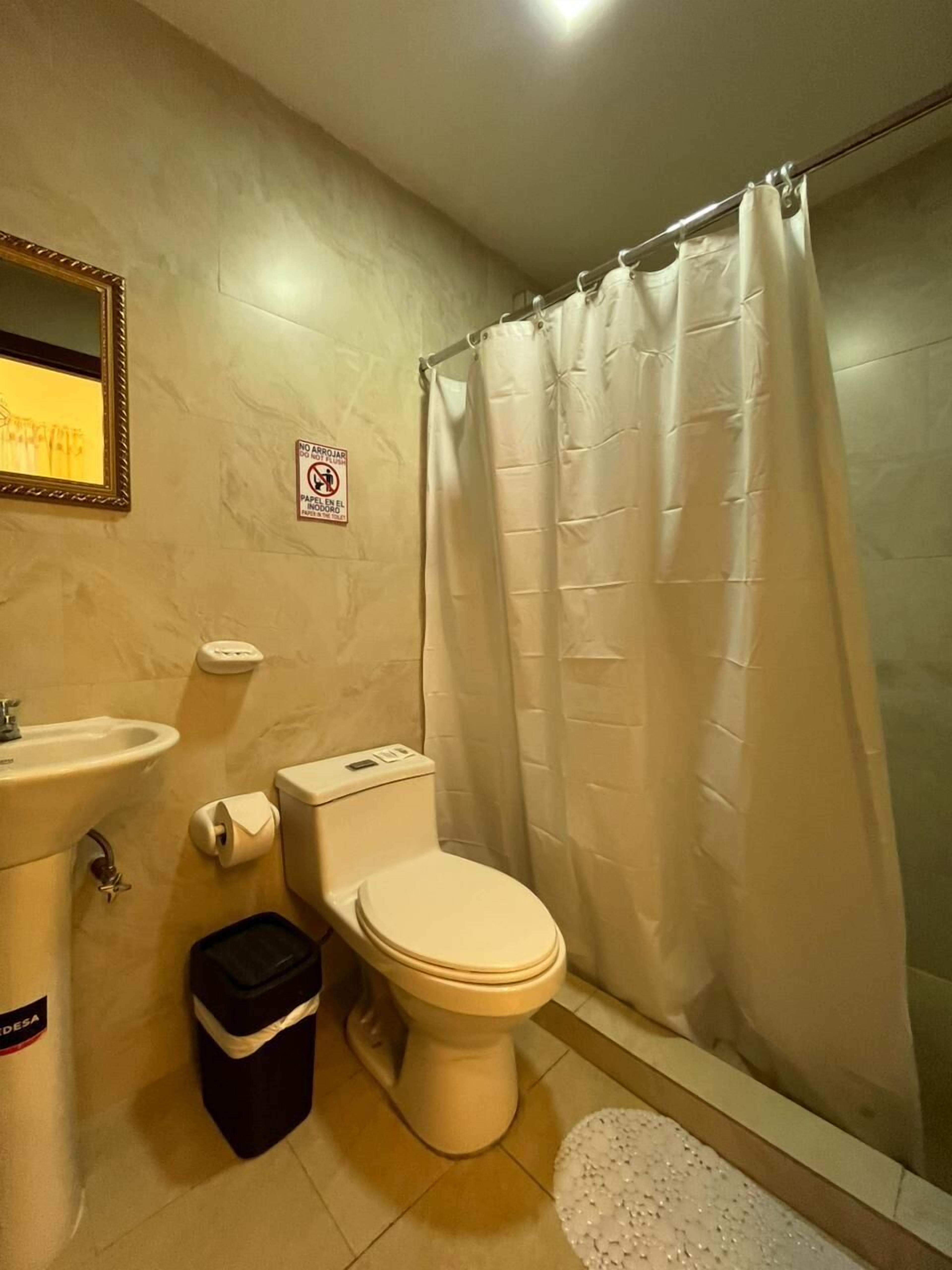 Un baño con inodoro, lavamanos y cortina de ducha.