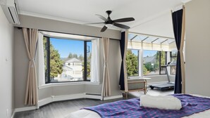 A bedroom with a bed, a ceiling fan, a treadmill, and large windows. - Luxury 5BR Point Grey | Jericho Beach + Downtown (Vancouver)