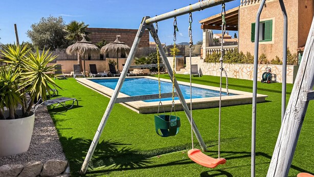 Un jardin avec une piscine, une balançoire et une pelouse bien entretenue.