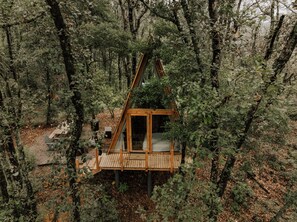 A wooden treehouse with a platform and a door, surrounded by dense forest. - WANDER CABINS MIneral del Chico (Mineral del Chico)