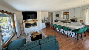 Una cocina moderna con una isla central, taburetes de bar y un comedor con sofá.