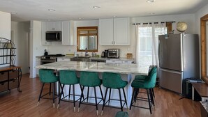 Una cocina moderna con una isla central, taburetes de bar y un refrigerador de acero inoxidable.