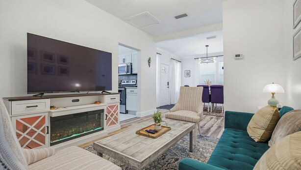 Ein Wohnzimmer mit Fernseher, Sofa, Sesseln, einem Couchtisch und einem Kamin.