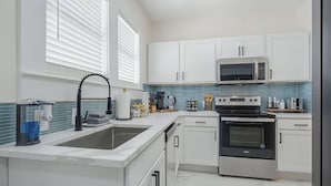 Eine moderne Küche mit weißen Schränken, einem Edelstahlbackofen, einer Mikrowelle und einem Spülbecken mit Armatur.