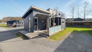 En modern, enplansbyggnad med ett platt tak, stora fönster och en liten veranda.
