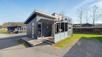 A modern, single-story building with a flat roof, large windows, and a small porch area.