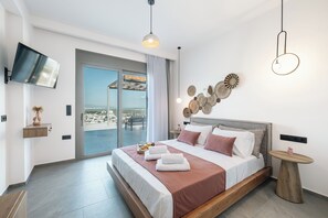 Une chambre d’hôtel moderne dotée d’un grand lit, d’une télévision, d’un balcon avec vue et d’œuvres d’art décoratives au mur.